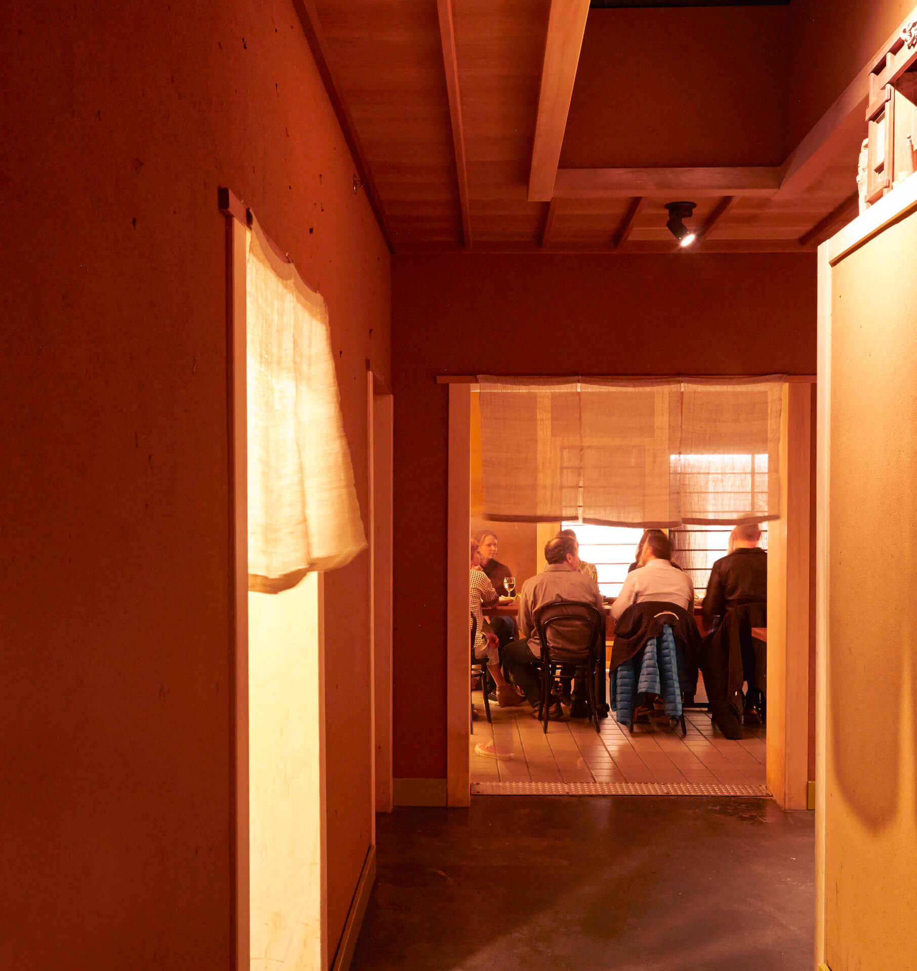 Photograph of the interior of Rintaro; a warmly-lit restaurant constructed using traditional Japanese carpentry and materials.