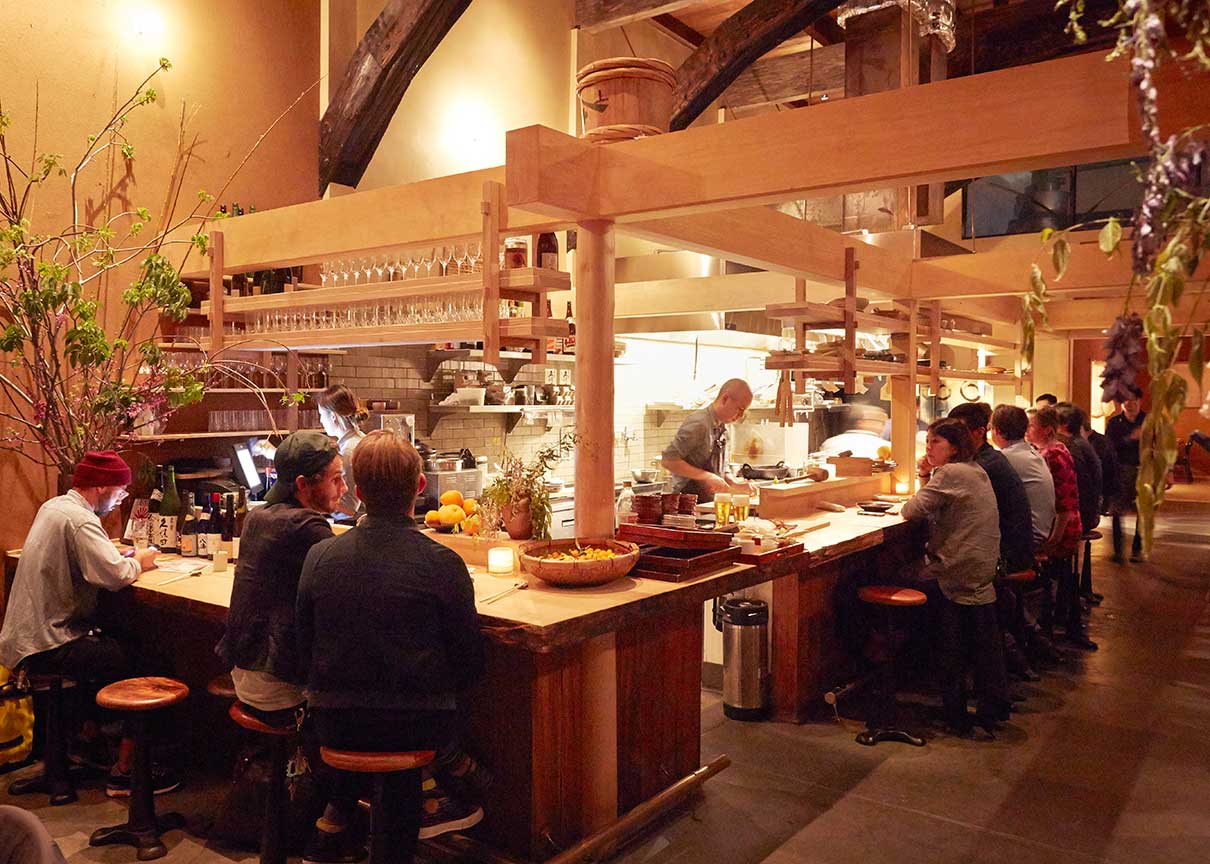 Photograph of the interior of Rintaro; a warmly-lit restaurant constructed using traditional Japanese carpentry and materials.